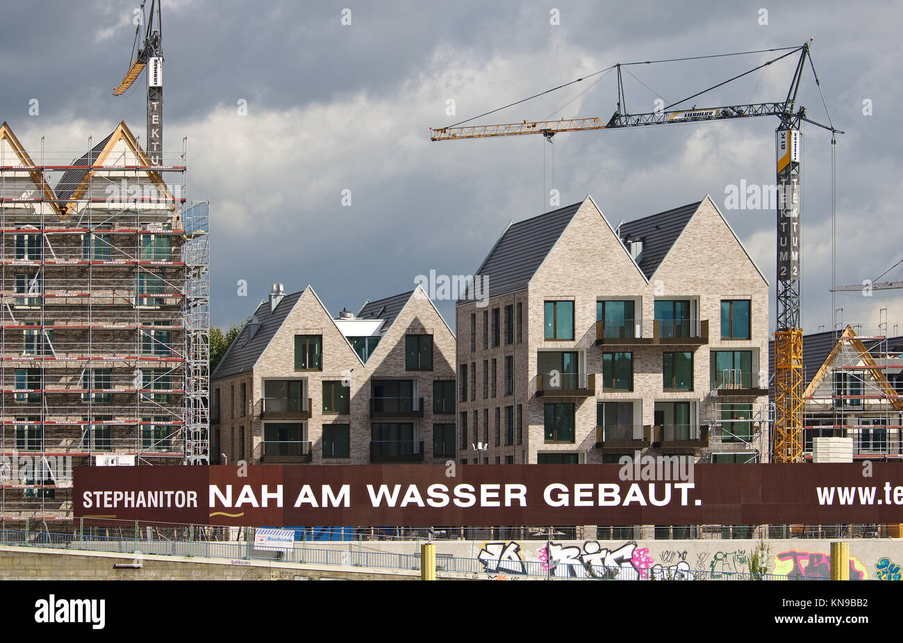 Bremen, Germany - September 14th, 2017 - Riverside construction site with cranes, scaffolding, partly and fully completed residential buildings and si Stock Photo