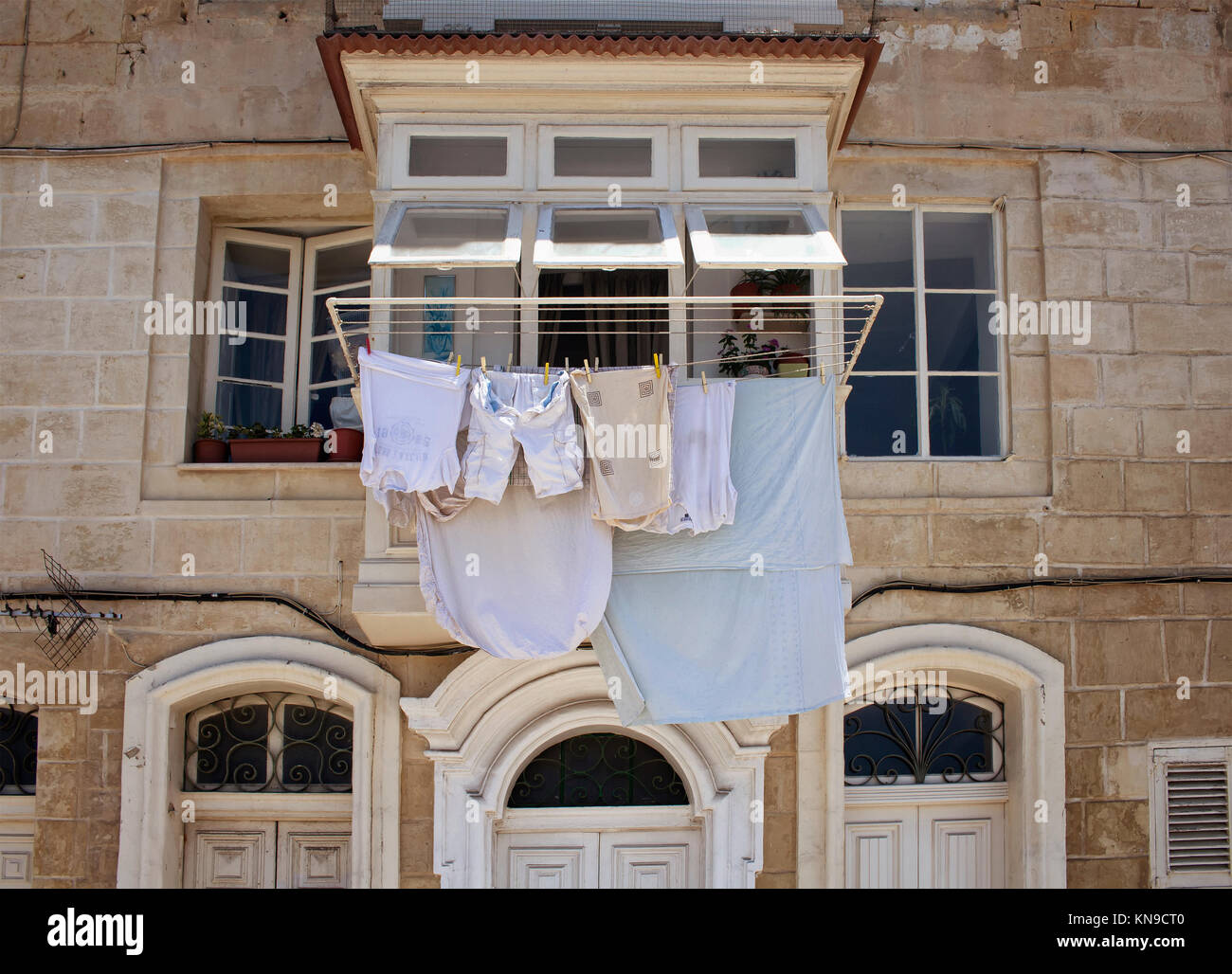 View of a historical, typical Valletta building in Malta. Hanging out clothes outside to dry reflects region's culture and lifestyle. Stock Photo