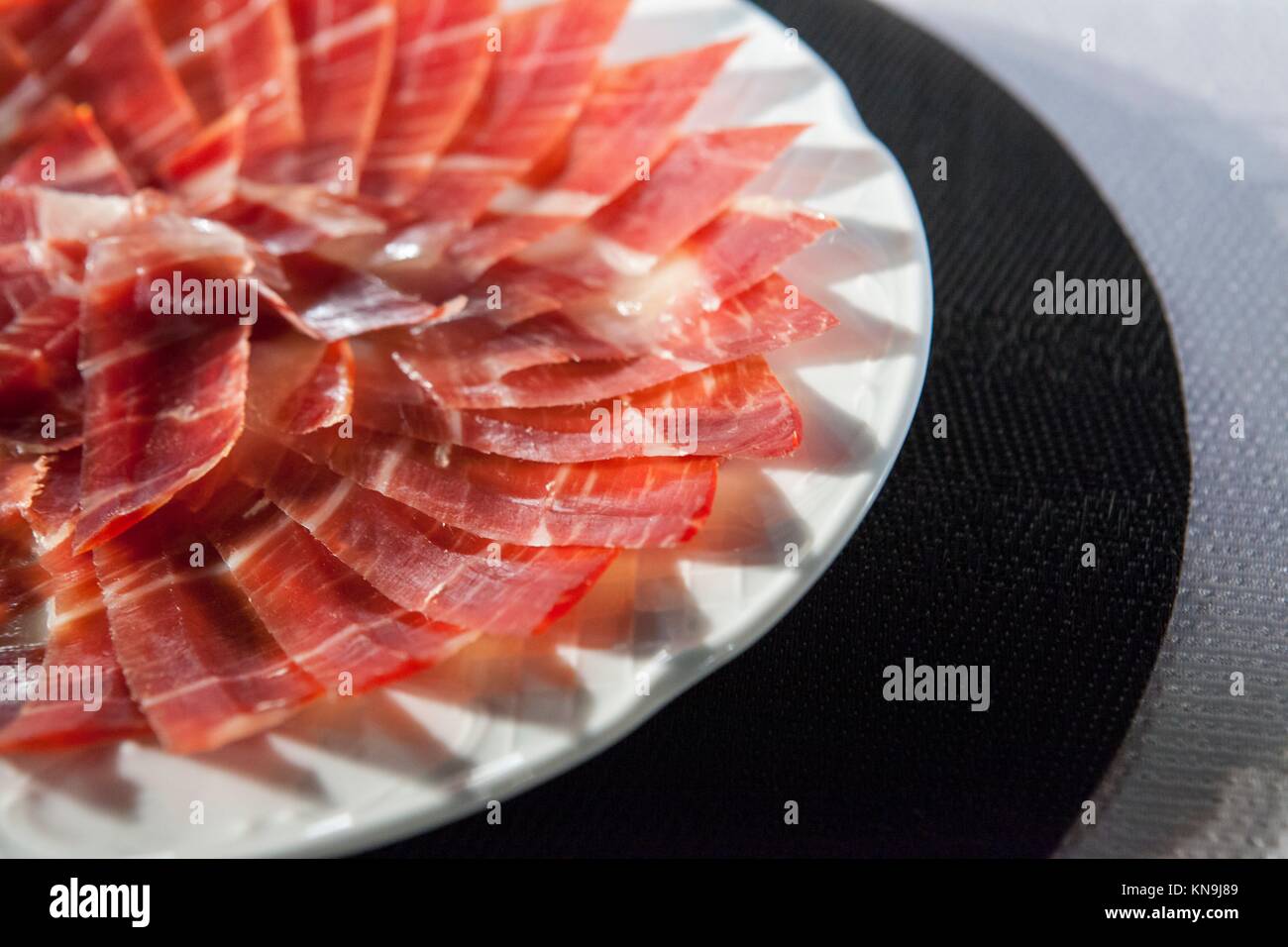 Circular decorative arrangement of iberian cured ham on plate. Selective focus point. Stock Photo