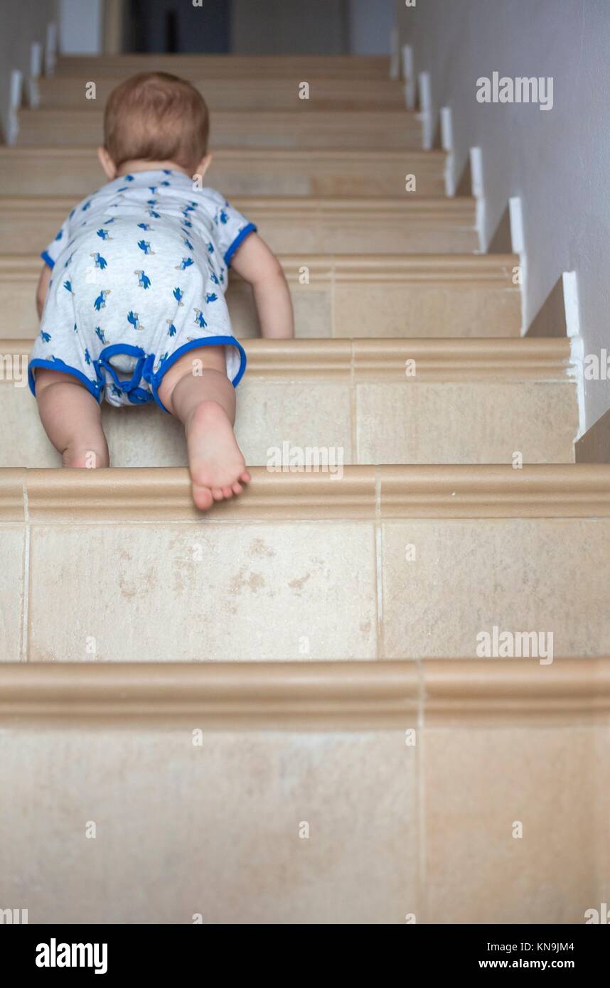 Baby boy crawling up the stairs. Low angle view. Stock Photo