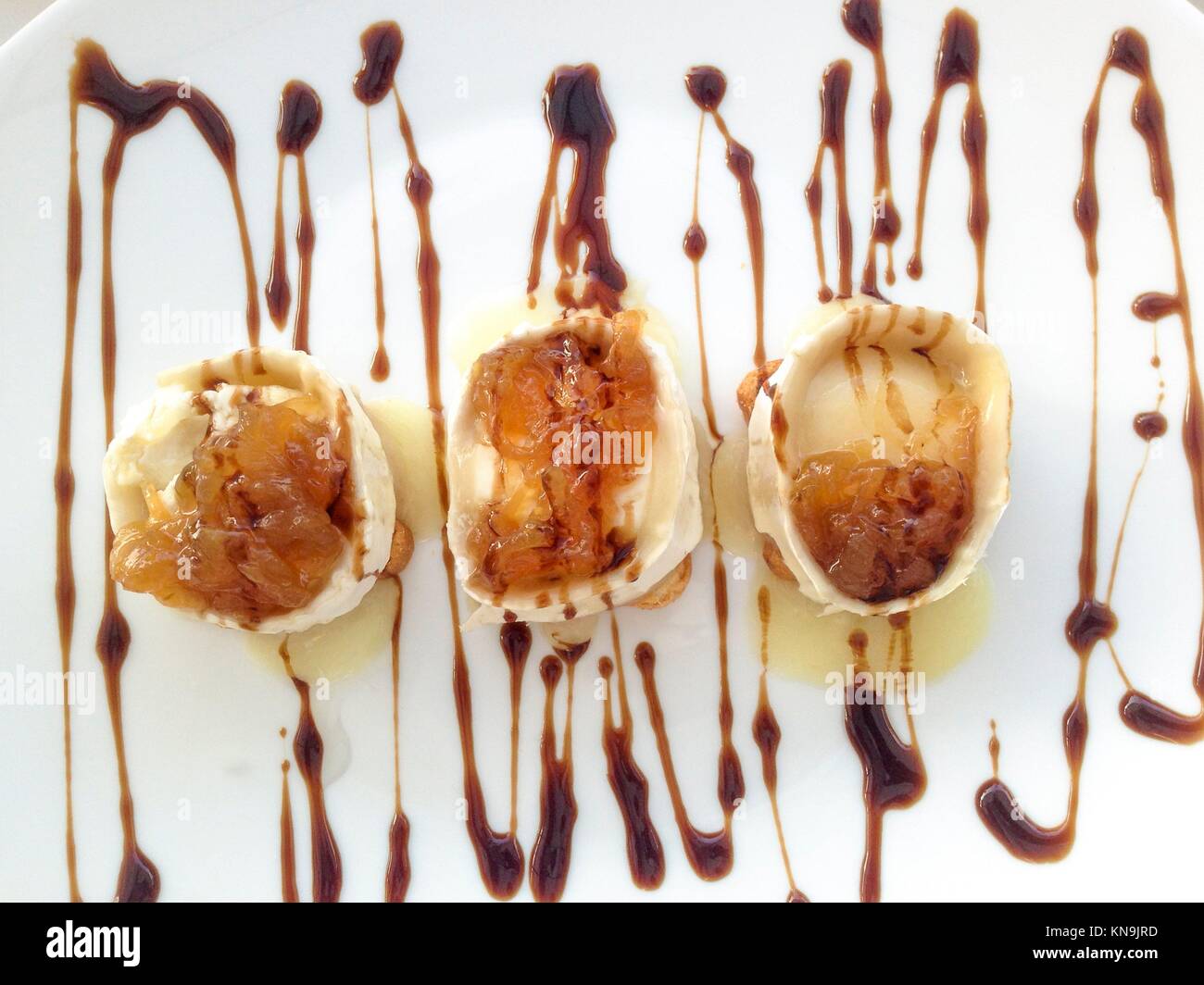 Goat cheese rolls with caramelized onions decorated with black vinegar sauce. Spanish tapa. Stock Photo