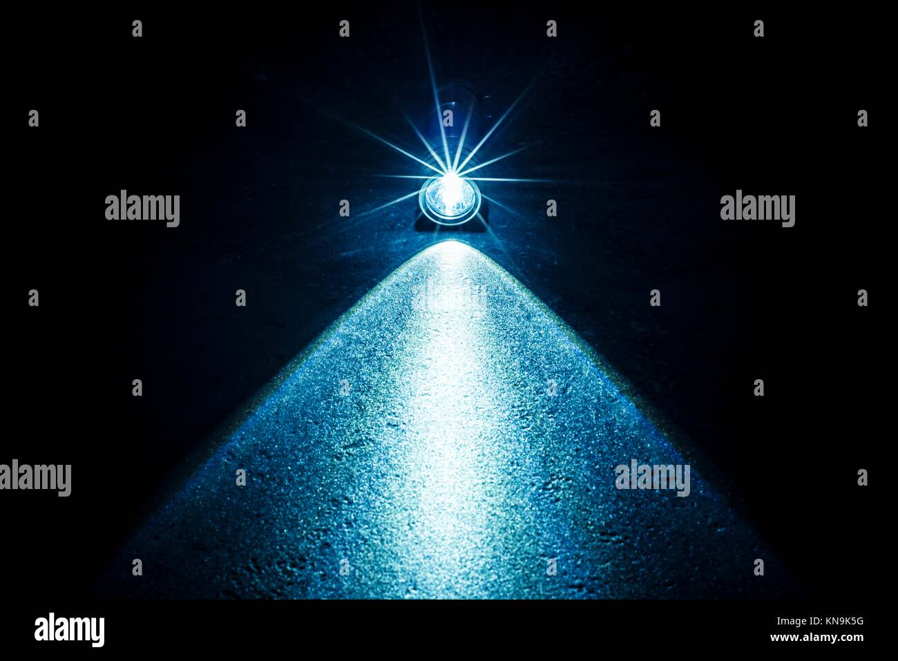 Flashlight and a beam of light in darkness. A modern led light with bright projection on dark stone surface. Surface with copy space. Stock Photo