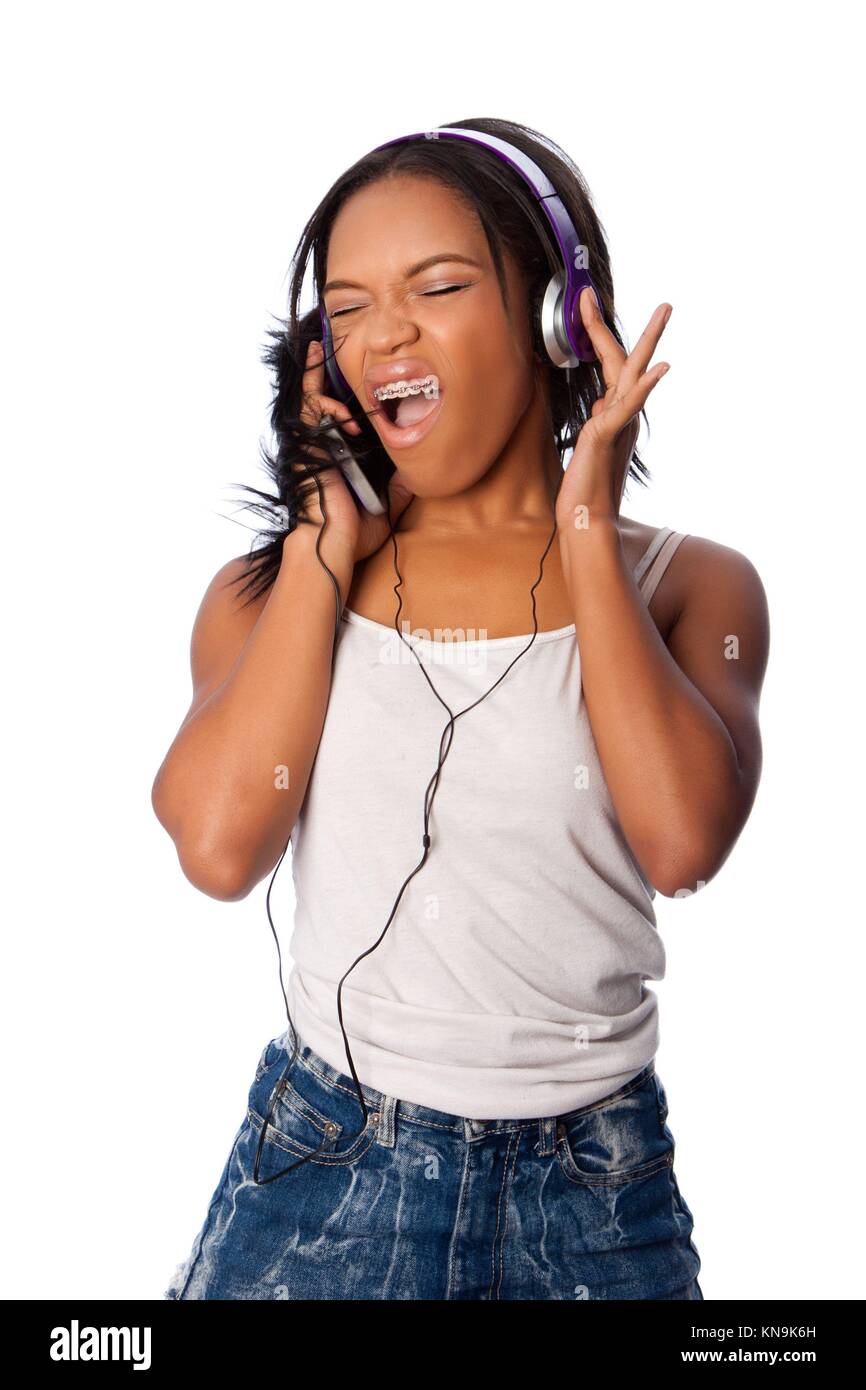 Beautiful teenager happily singing along jamming while listening to music, on white. Stock Photo