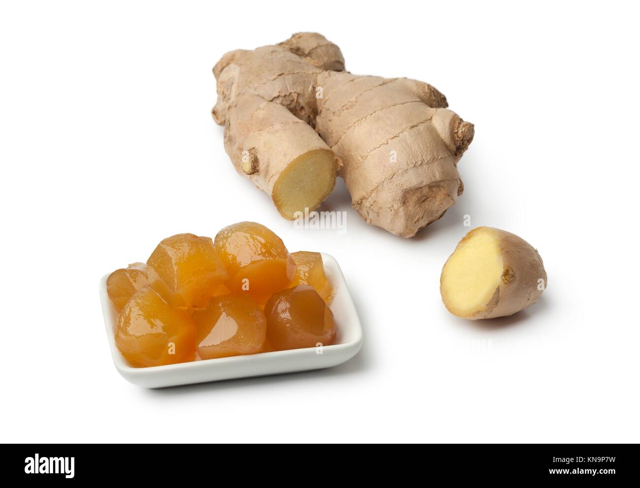 Dish with stem ginger in syrup and fresh gingerroot on white background