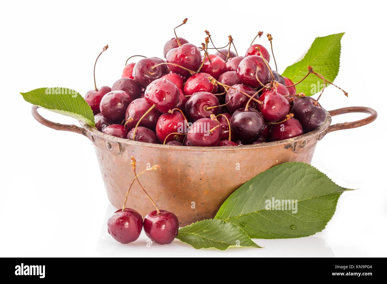 Copper pot with ripe cherries isolated on white background Stock Photo