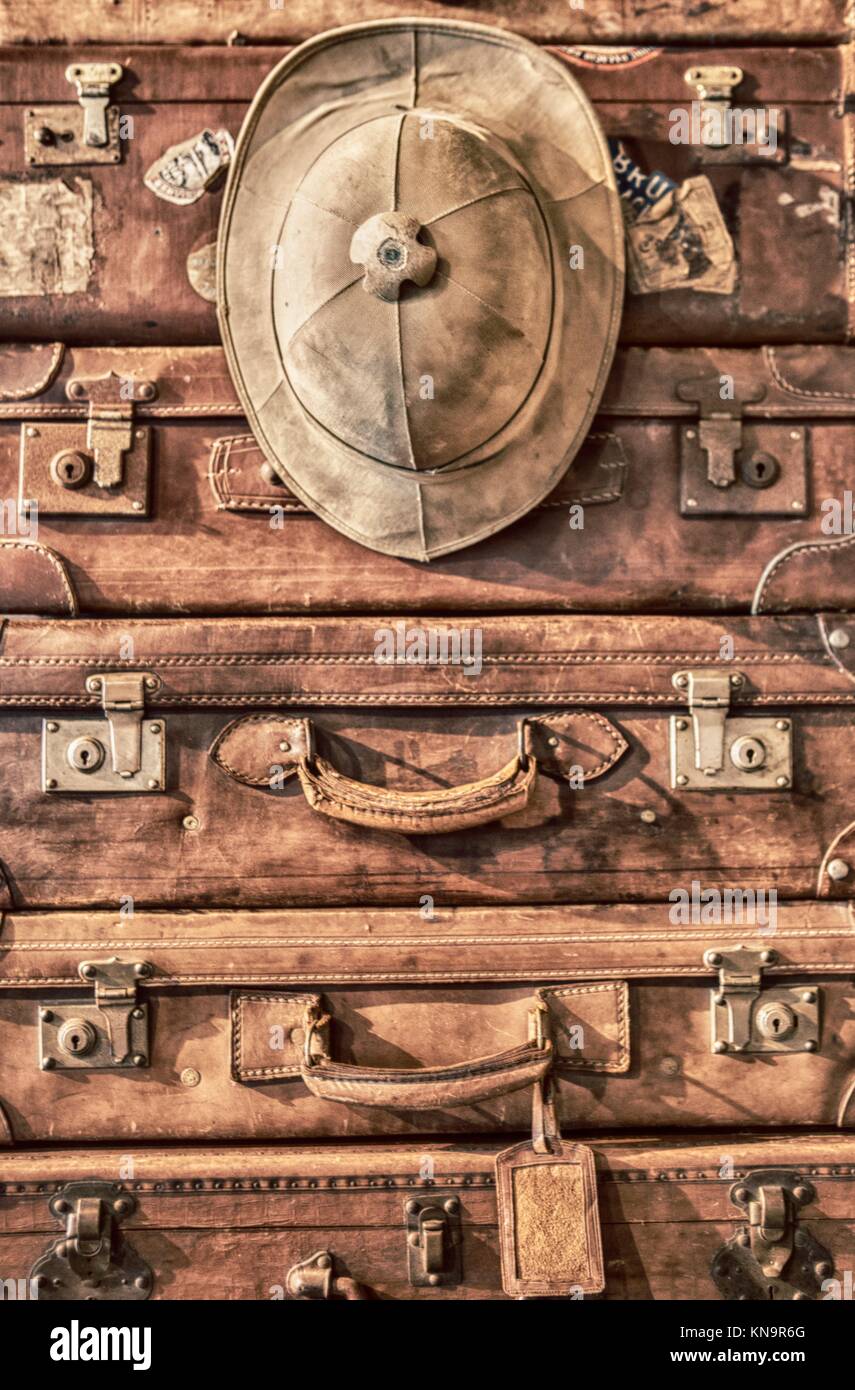Pile of antique leather luggage suitcases with Salacot hat. Analog filtered. Stock Photo