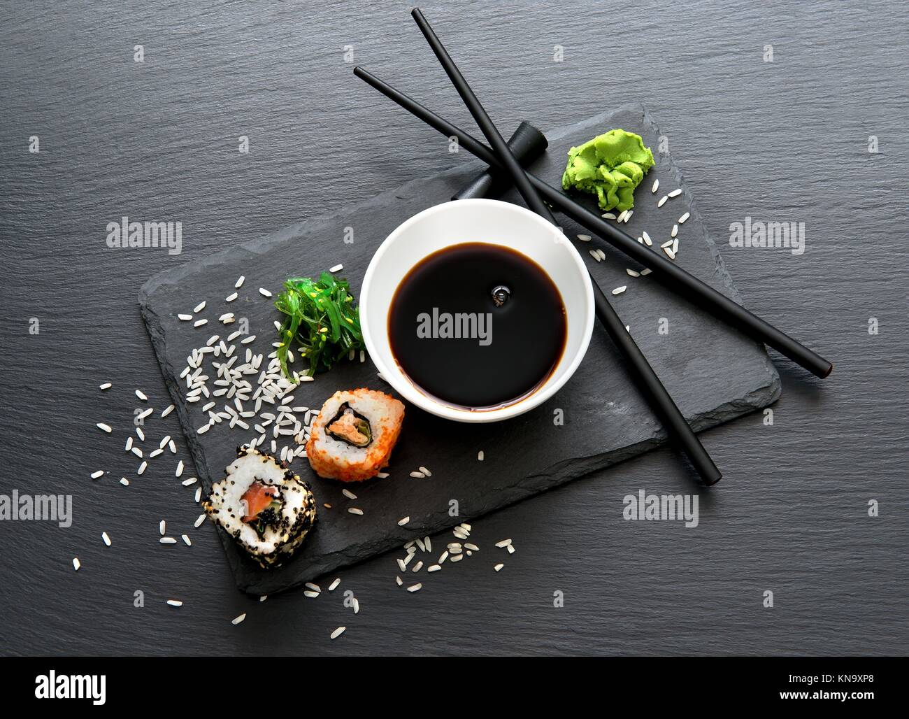 Rolls with sauce and chopsticks on a slate table. Stock Photo