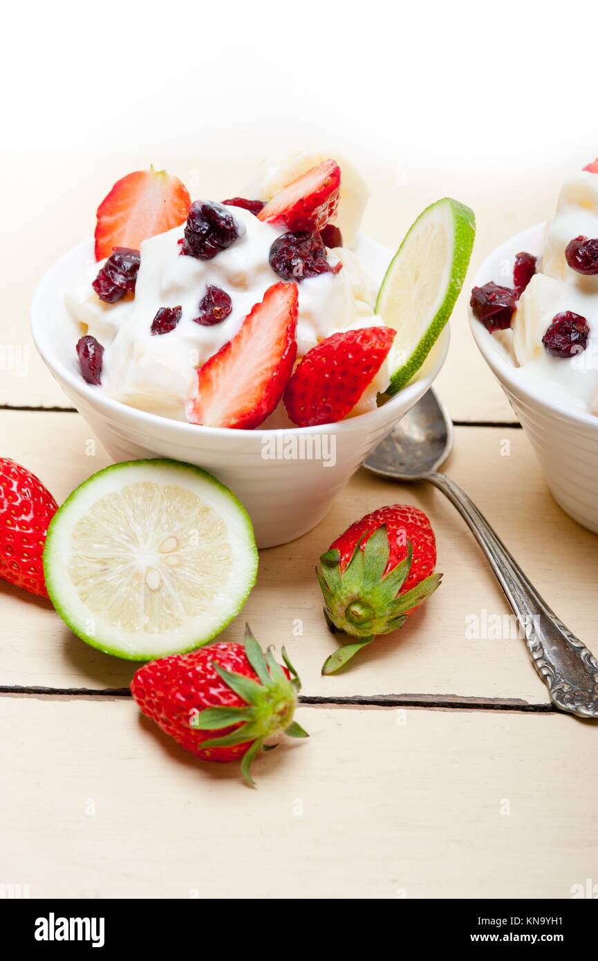 fruit and yogurt salad healthy breakfast over white wood table Stock