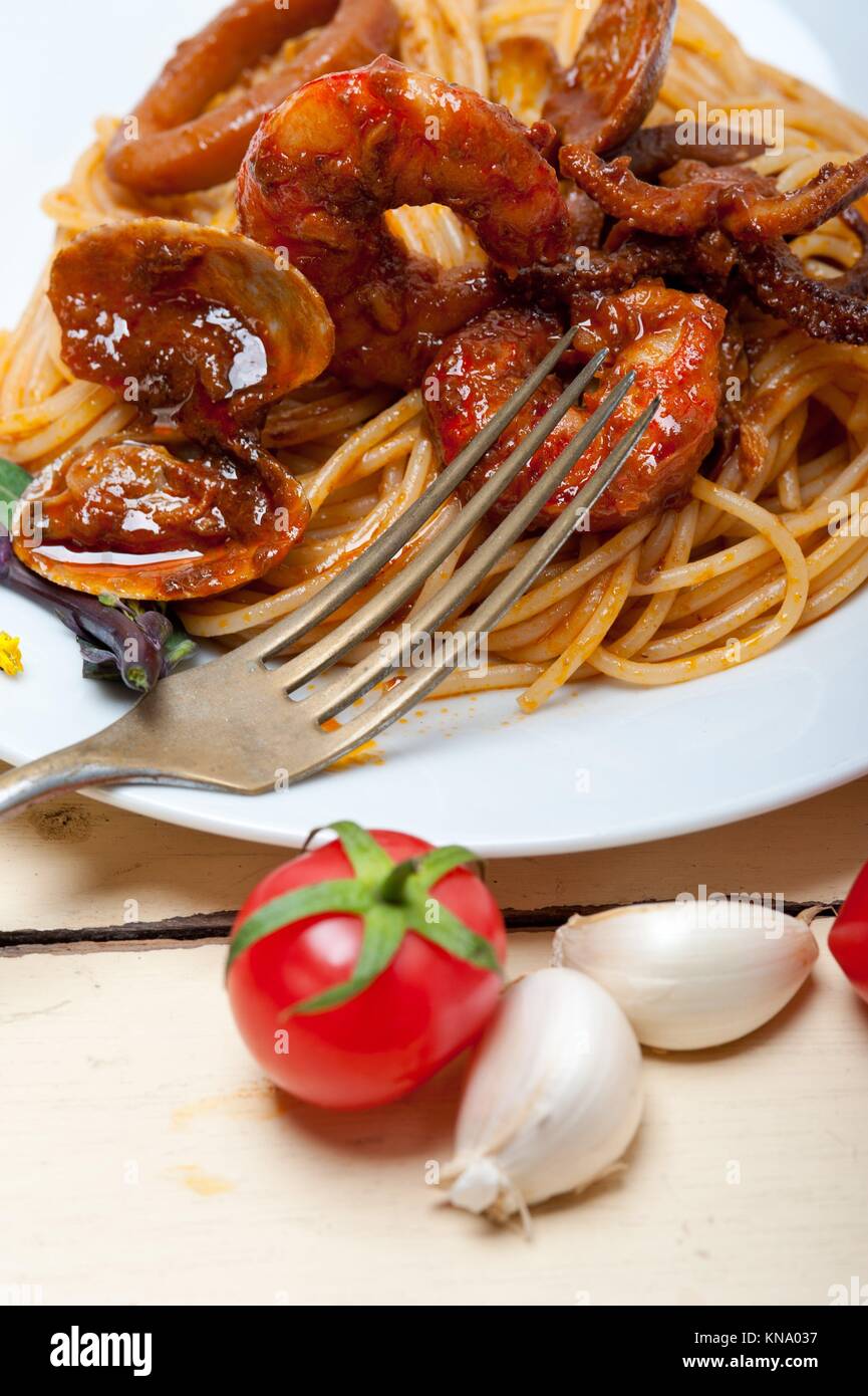 Italian seafood spaghetti pasta on red tomato sauce over white rustic