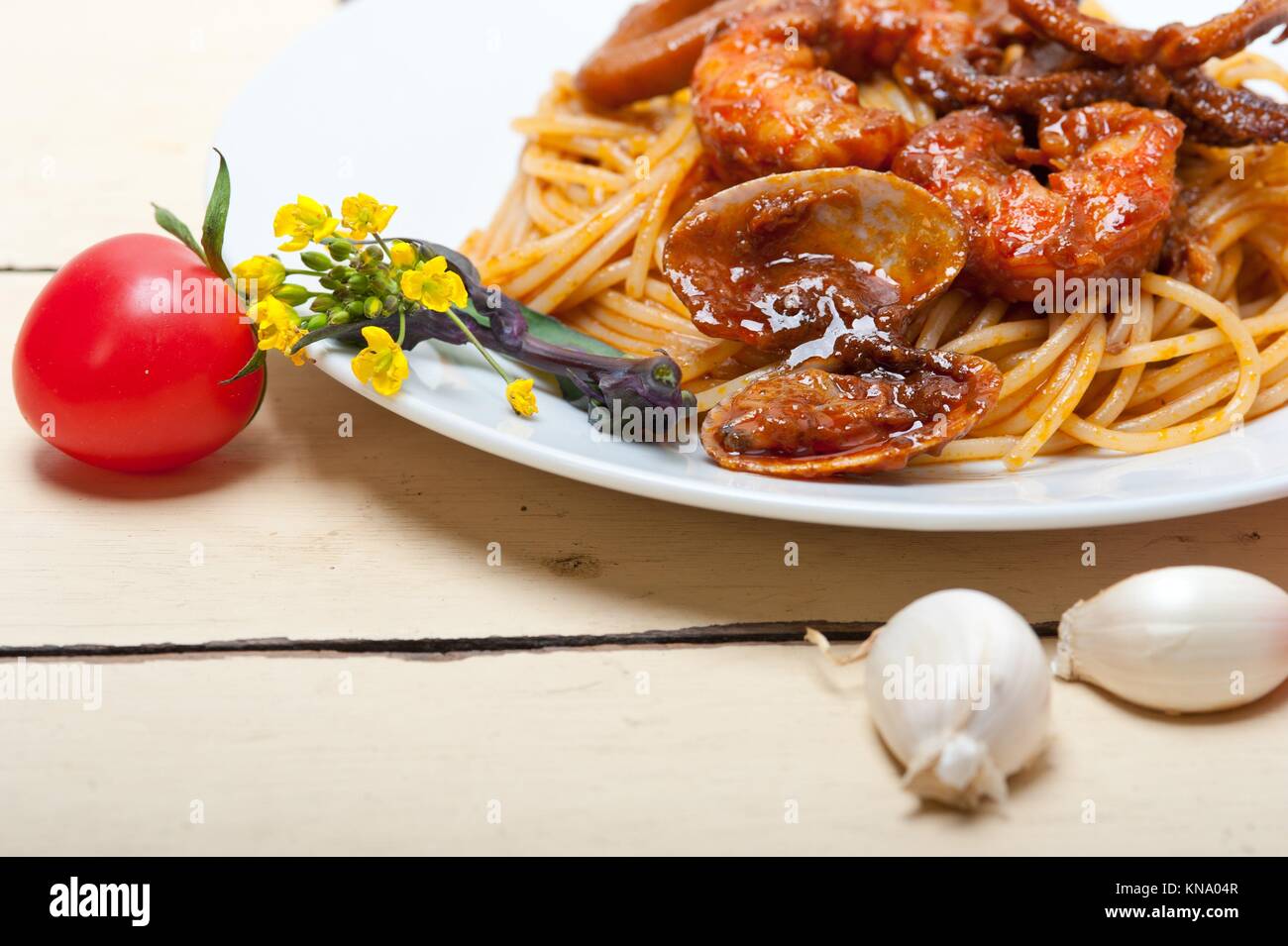 Italian seafood spaghetti pasta on red tomato sauce over white rustic