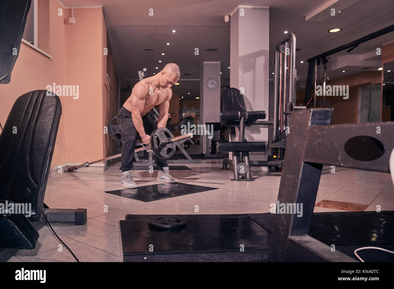 one bodybuilder, exercise T-bar row, gym interior, fitness equipment. Stock Photo