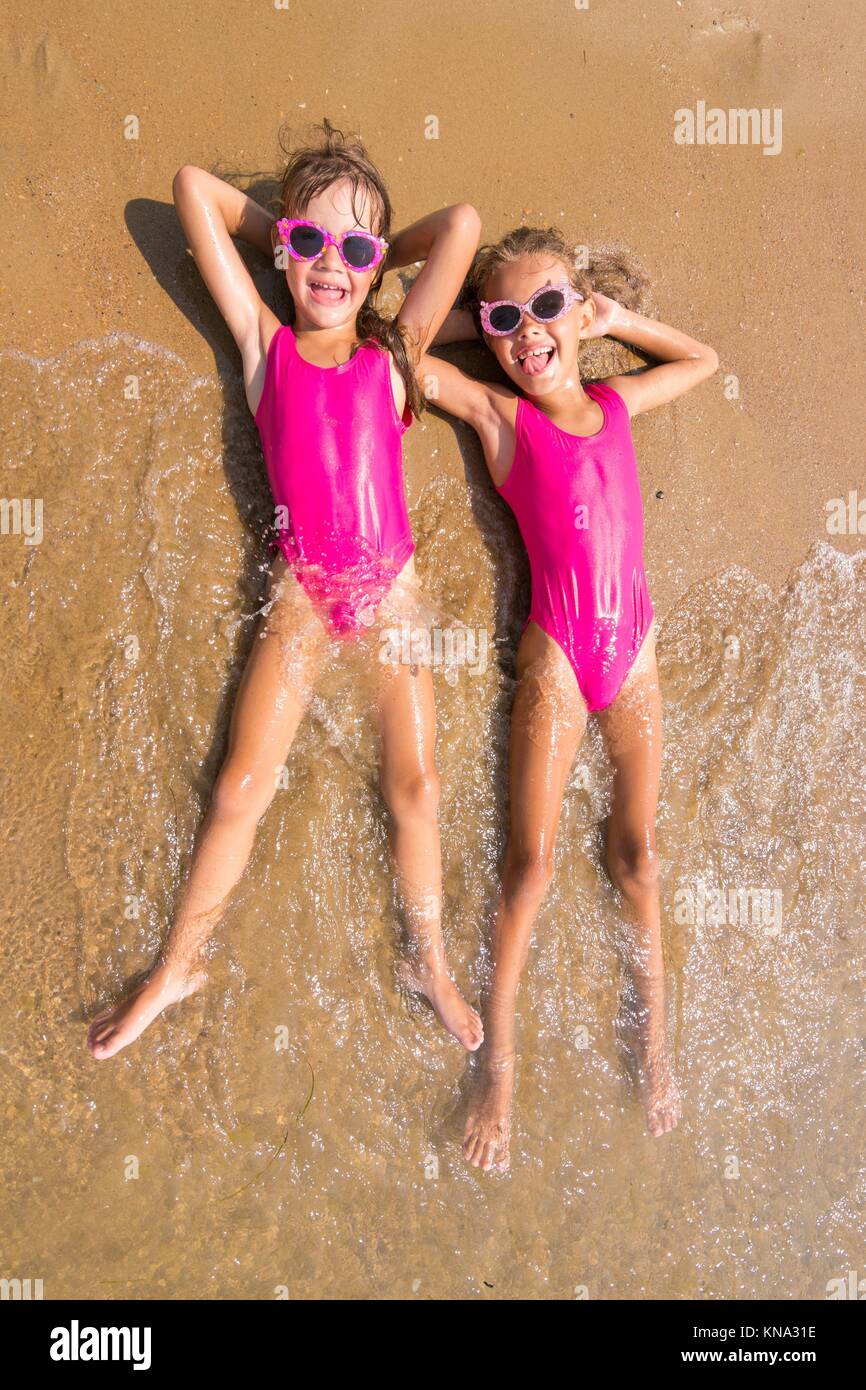 Two girls lie on his back on the surf of the sea sandy beach Stock