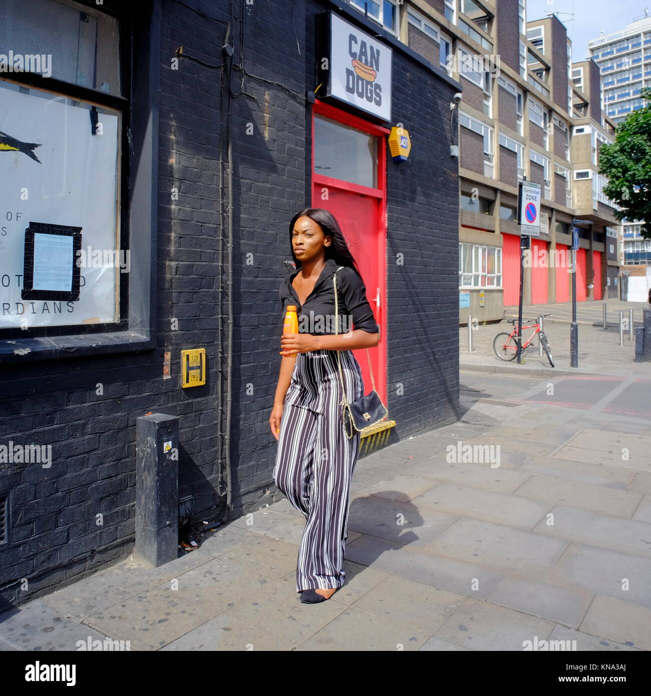 Attractive stylish Afro-Caribbean woman walking down street in London, England, UK Stock Photo