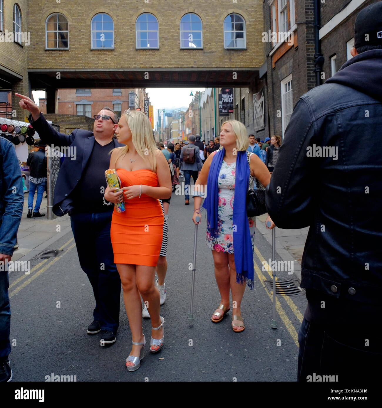 Attractive young blonde woman wearing tiara with family on Brick Lane in Shoreditch, London, England, UK Stock Photo