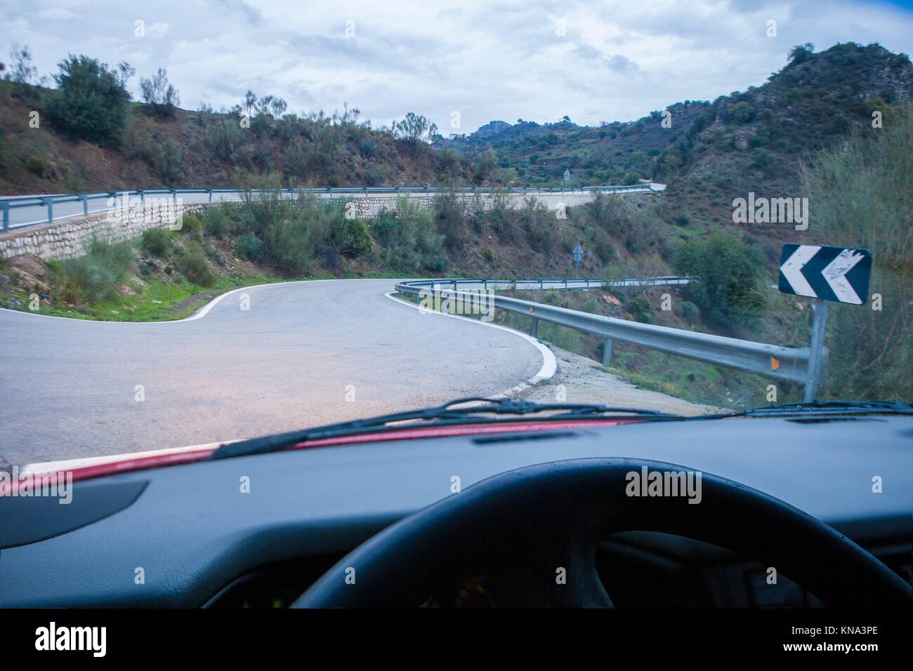 Driving by narrow mountain curvy road at sunset. Dangerous curvy driving concept. Stock Photo