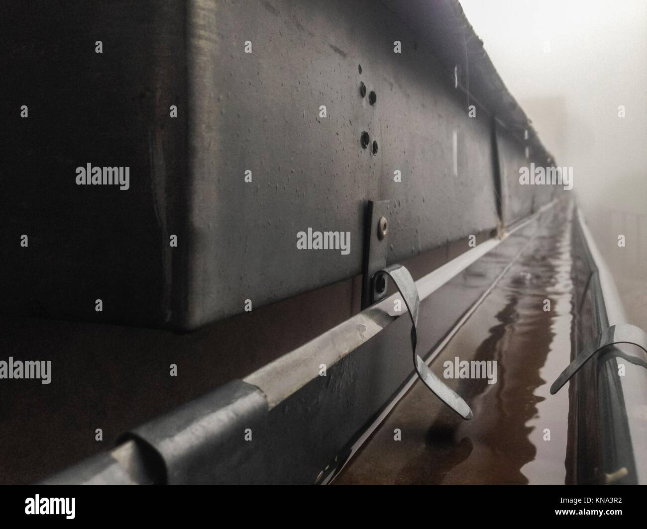 Gutter drainage system on the roof with dripping fog and rain. Closeup. Stock Photo