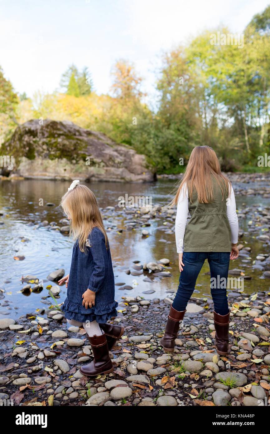 Siblings throw rocks in the McKenzie River together in the lifestyle shot of the children having fun playing. Stock Photo