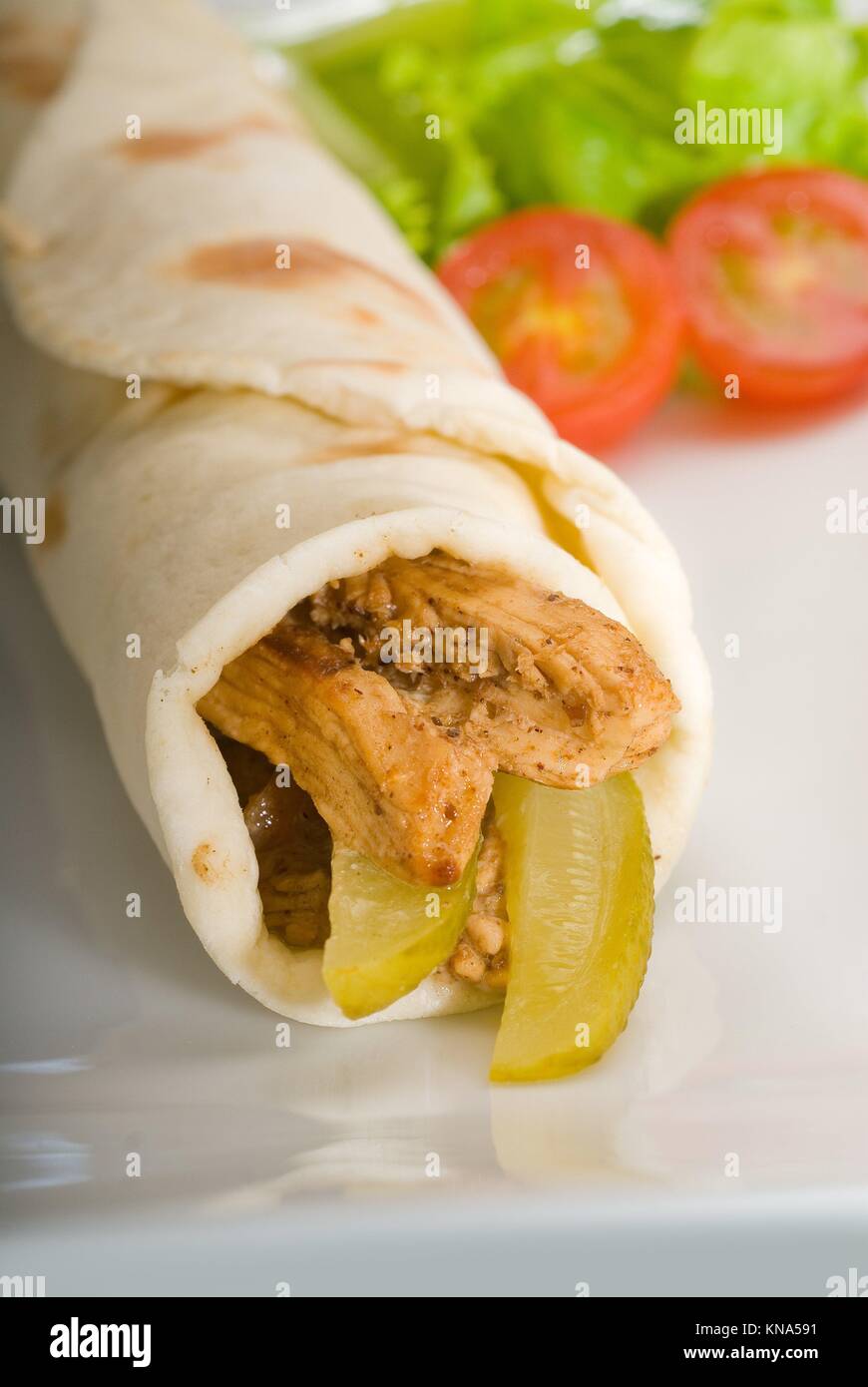 pita bread chicken roll with pickles cucumbers on a plate with pachino