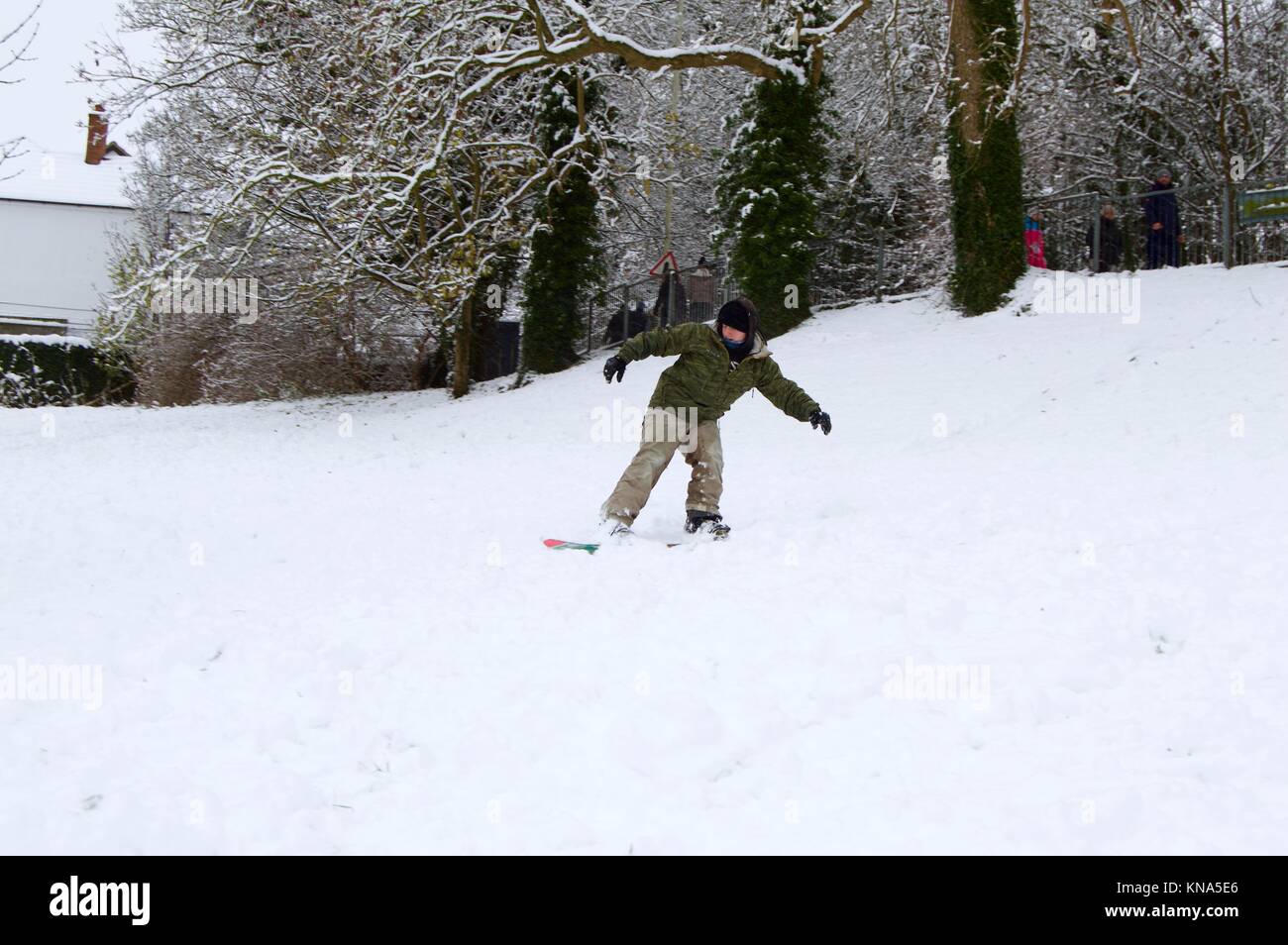 Children and adults enjoying the unexpected heavy snowfall by snowboarding and sledding down the