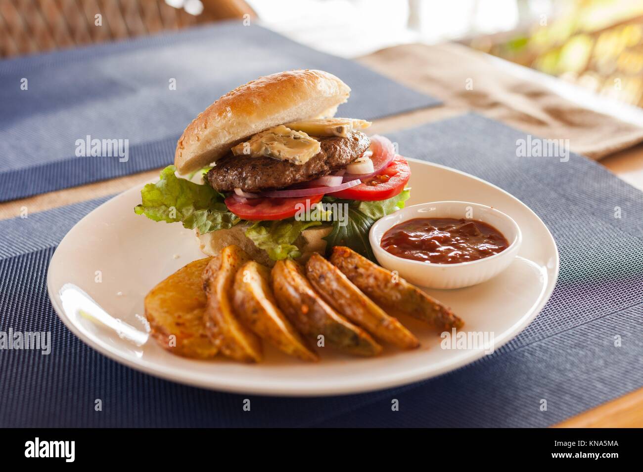 A Bleu (Blue) cheese hamburger with fries and barbecue sauce on a cafe