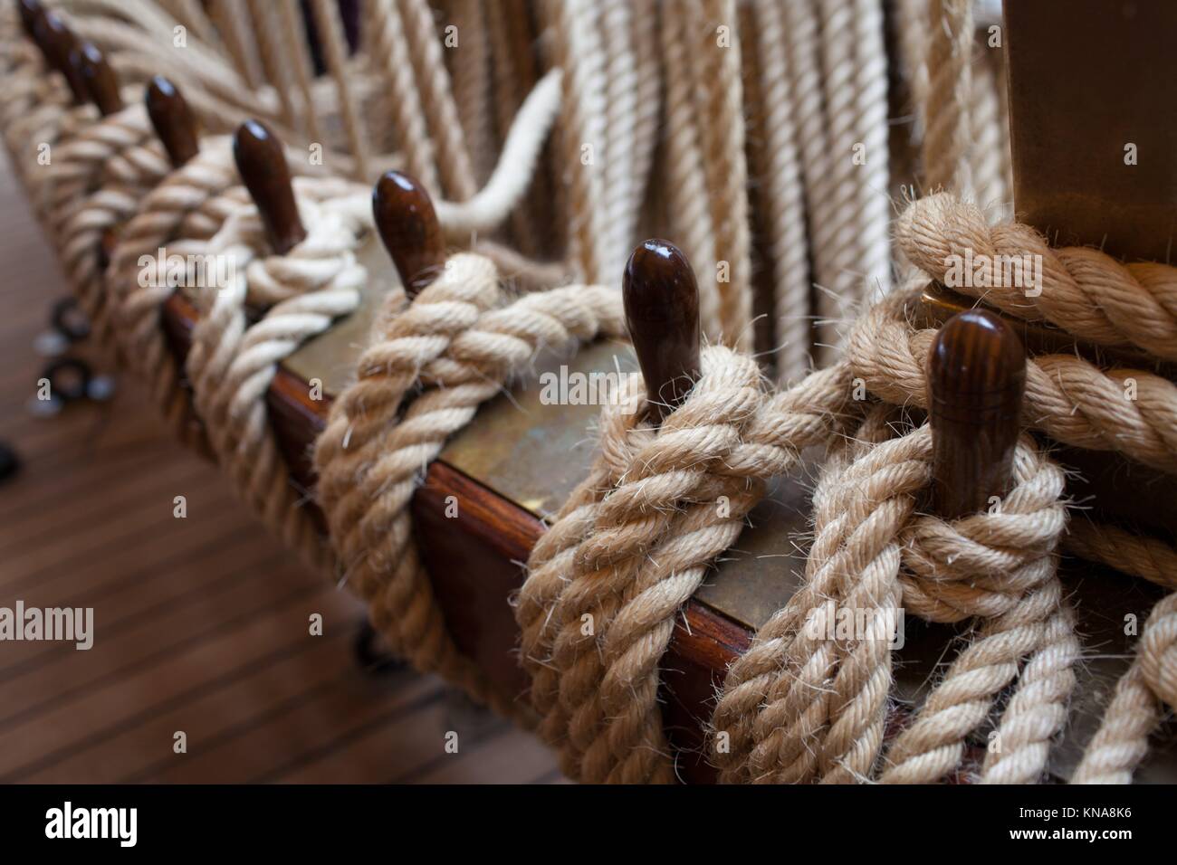 Hemp ropes tied to wooden beams, part of the rigging system of old sailboat, controling sails. Stock Photo