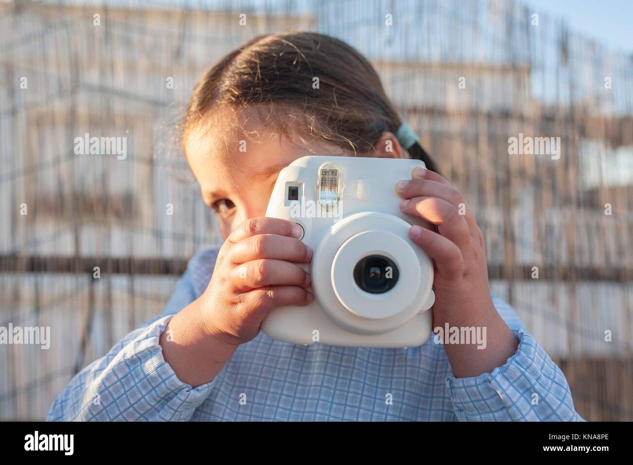 Cute little happy girl with instant picture photo camera. Outdoor. Stock Photo