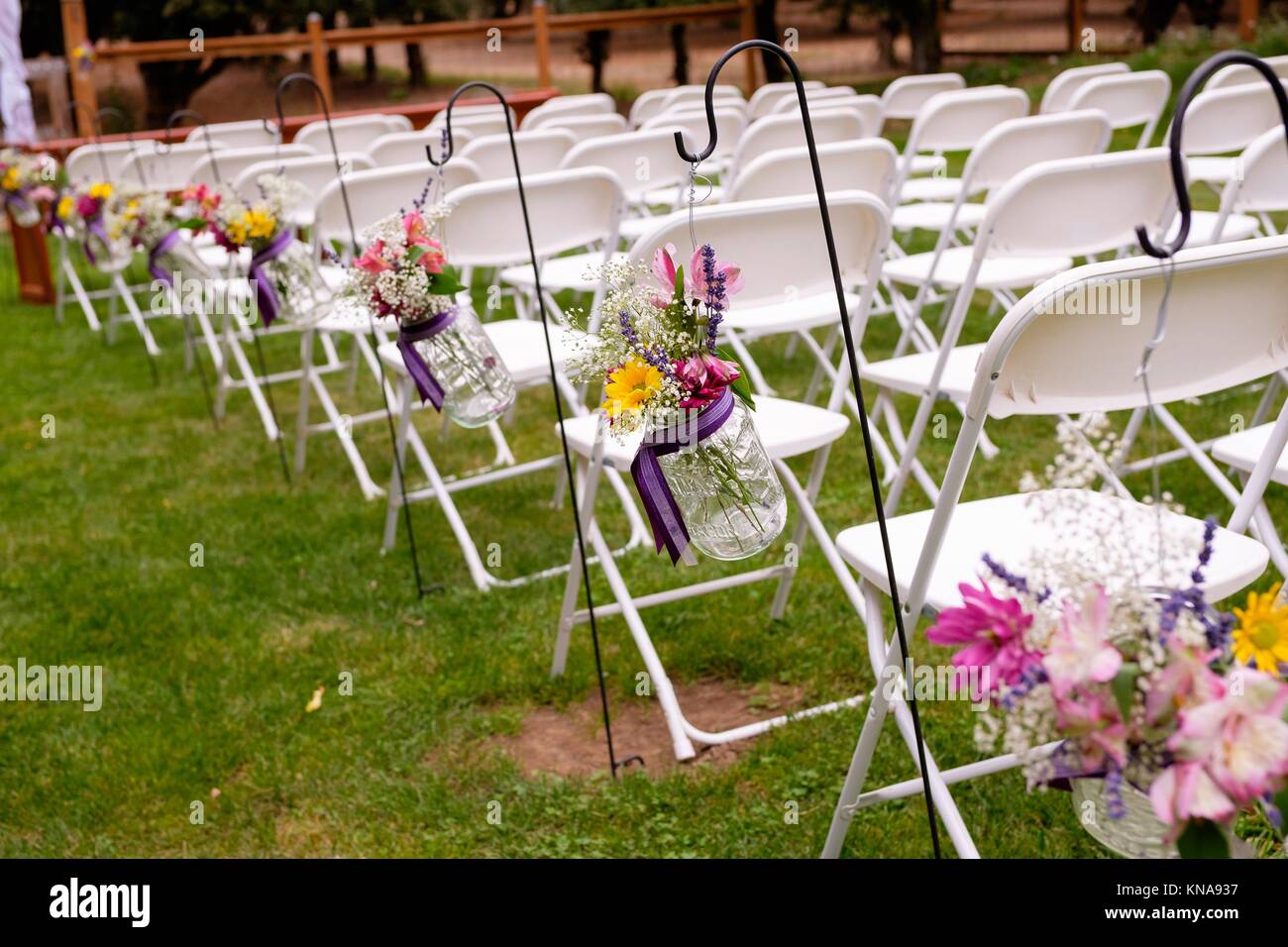 Ceremony Seating With White Chairs And Flowers At An Outdoor