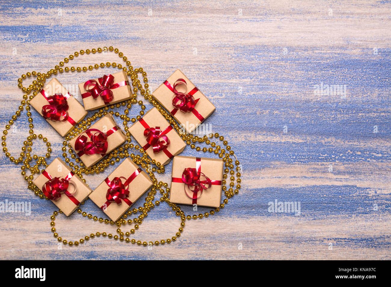 Group present wrapped in kraft paper and gold beads on a blue background Stock Photo