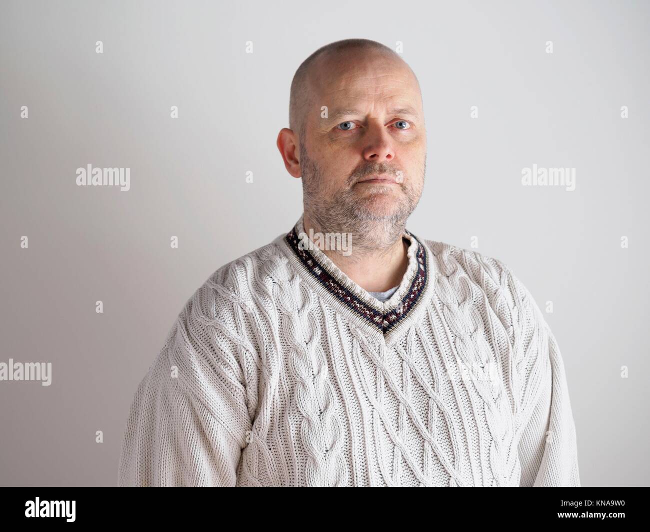 Portrait, casual looking caucasian male wearing a white pullover, he looks toward the camera, copy space is on the left. Stock Photo