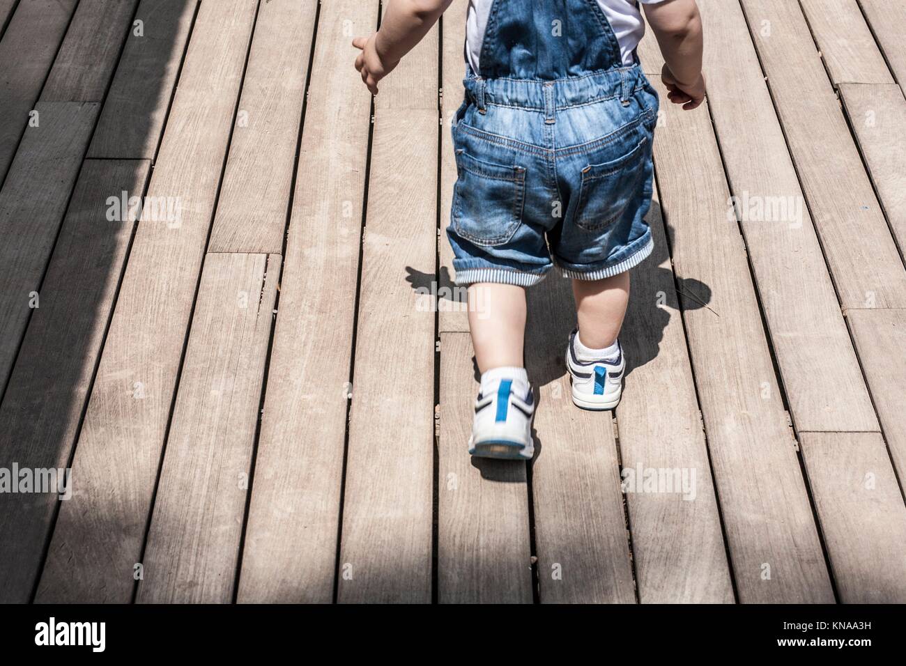 Baby boy learning to walk by himself. He is learning to overcome obstacles and new floor surface. Stock Photo