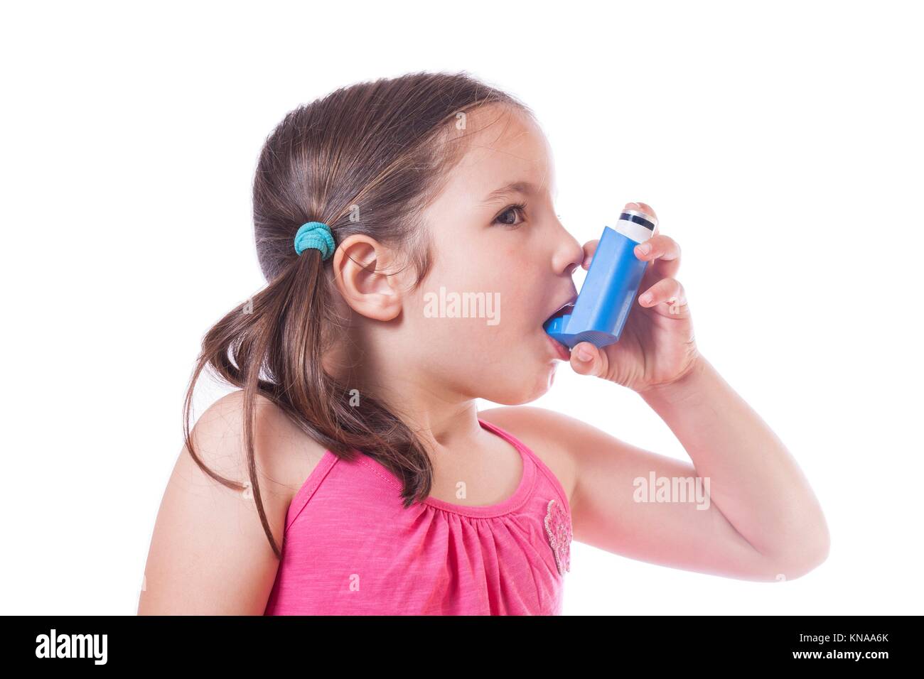 Little sick girl using medical spray for breath. Isolated over white background. Stock Photo