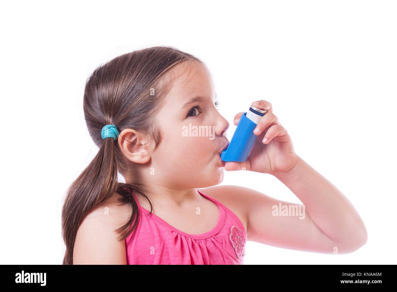 Little sick girl using medical spray for breath. Isolated over white background. Stock Photo