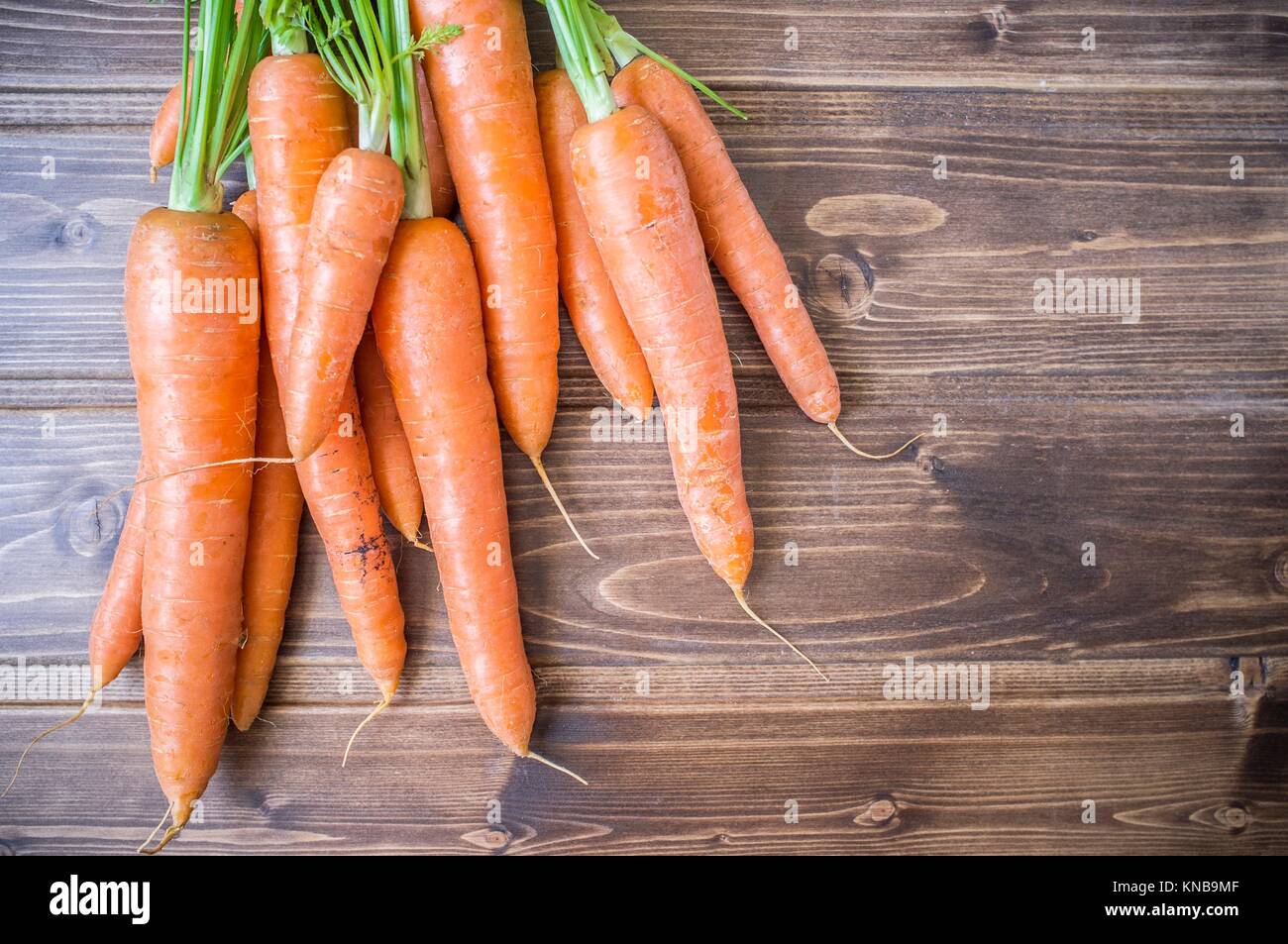 Some fresh carrots over wooden table from ecological farming. Closeup. Stock Photo