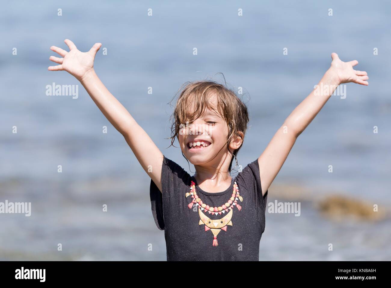 Girl with arms raised and smiling face. Stock Photo