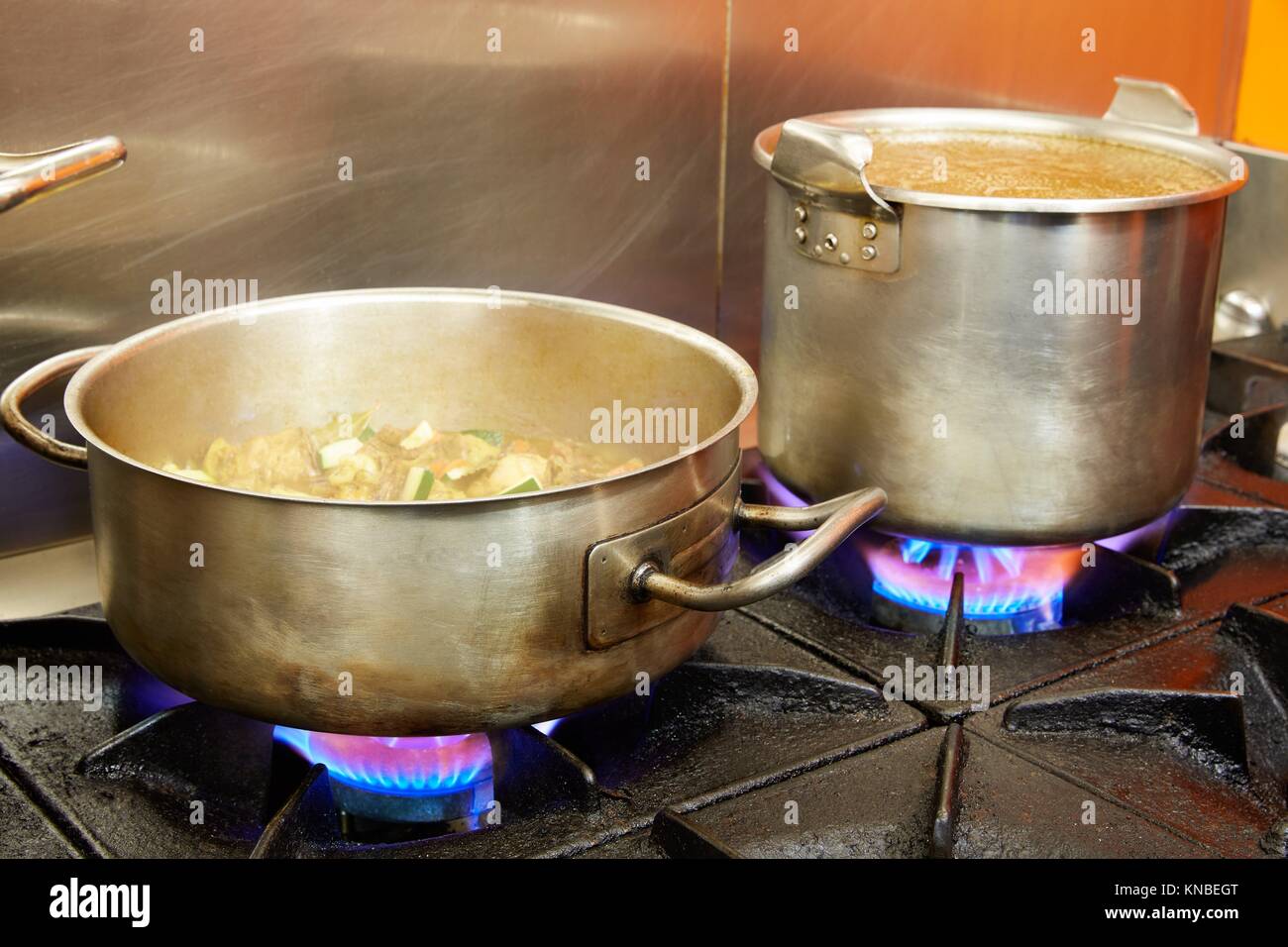Restaurant pro kitchen with stainless steel pans in fire Stock Photo