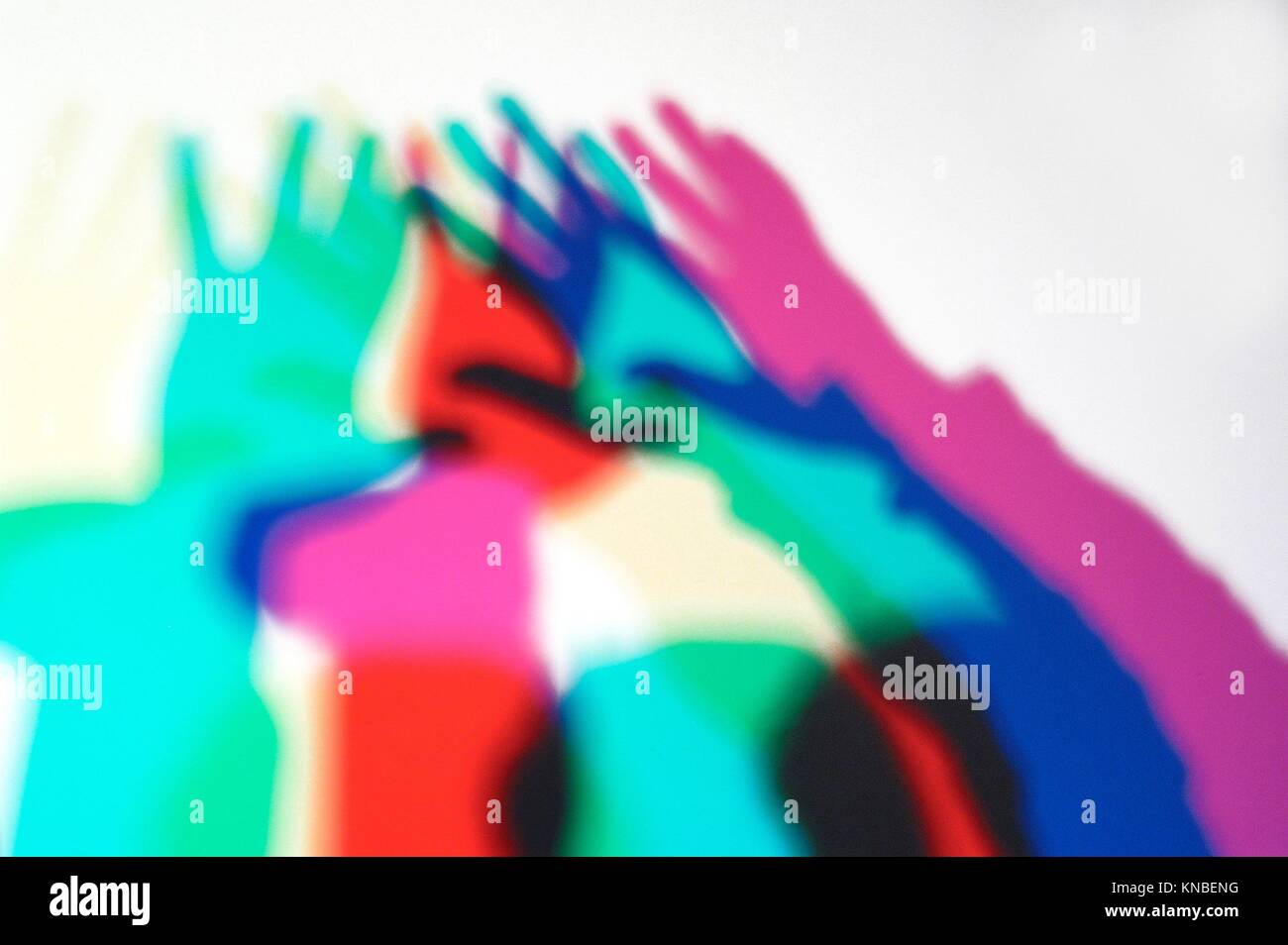 projection of several hands of people in front of a large spotlight. Stock Photo