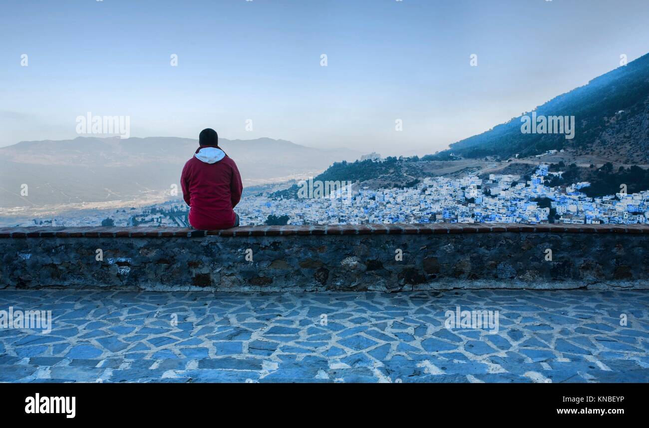 Tourist observing a panoramic view of blue city of Chefchaouen at rising, Morocco. Stock Photo