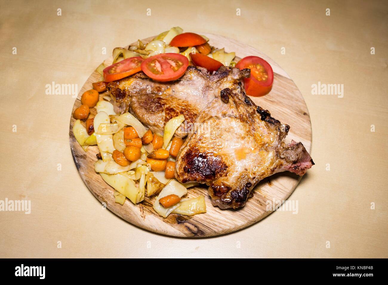 Pork meat with yellow beans ,carrots and tomatoes on a wooden board. Stock Photo