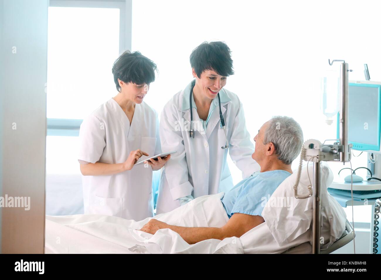 Patient in hospital room attended by a doctor, Hospital Stock Photo