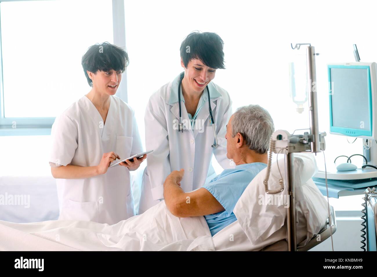 Patient in hospital room attended by a doctor, Hospital Stock Photo