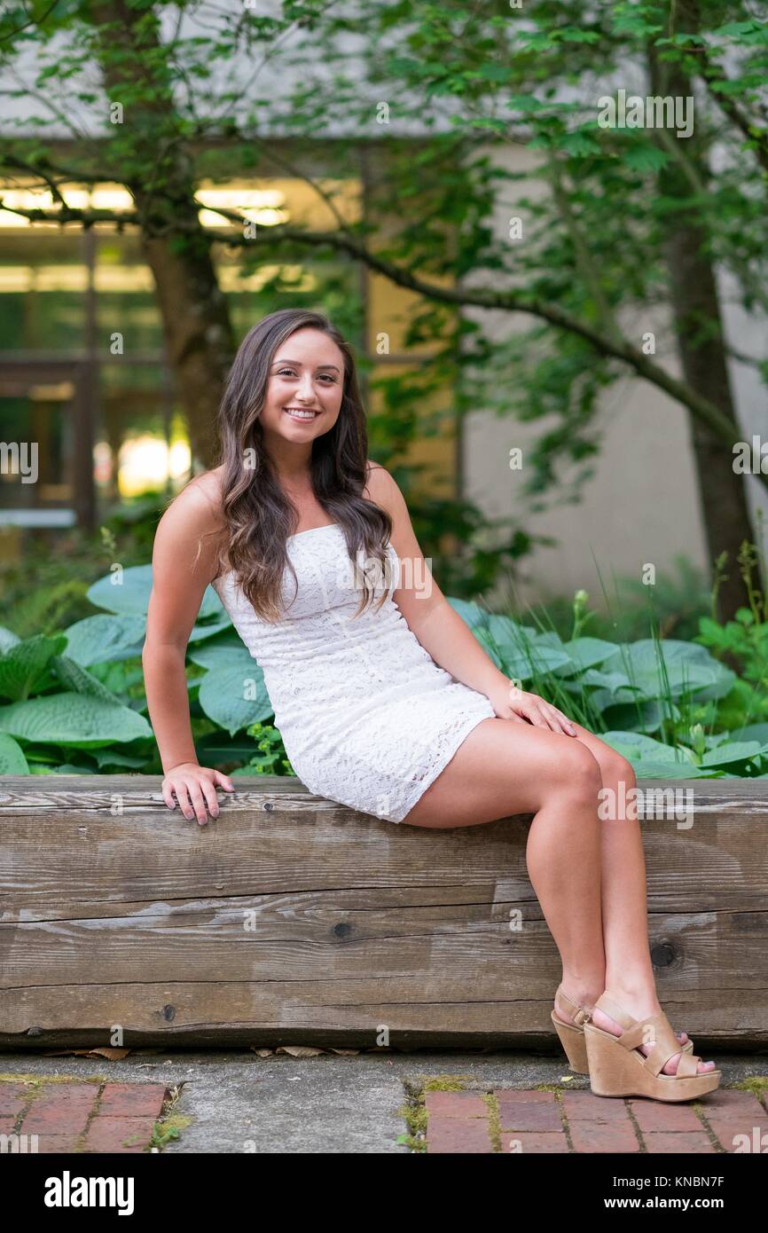 Lifestyle portrait of a college age model in a white dress on a