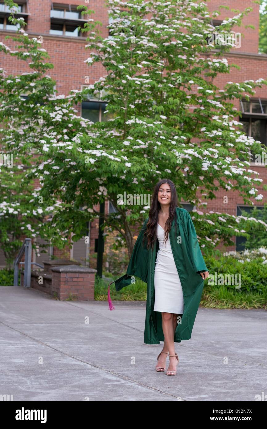 Beautiful college senior girl poses for graduation photos during the Spring on a university campus during the Spring in Oregon. Stock Photo