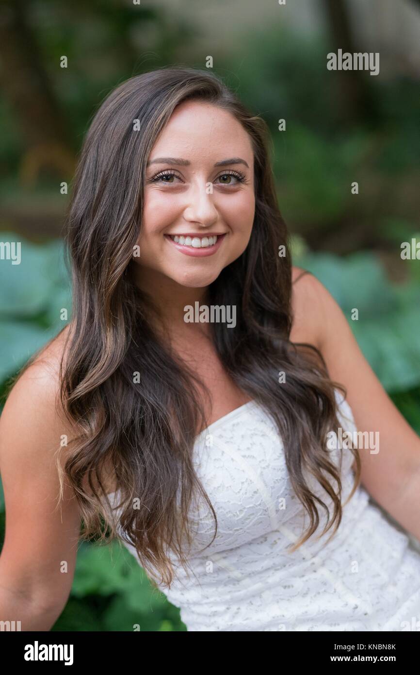 Lifestyle portrait of a college age model in a white dress on a
