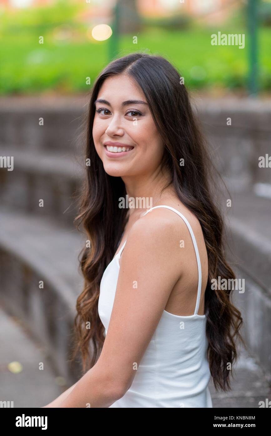 Lifestyle portrait of a college age model in a white dress on a