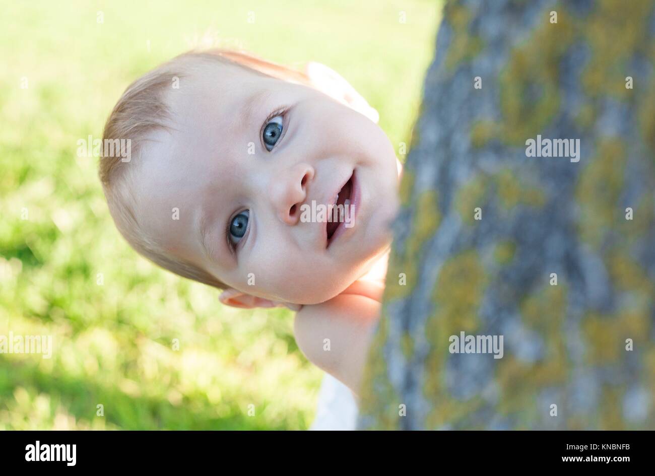 1 year baby boy playing hide-and-seek on swimming pool grass. Baby development concept. Stock Photo