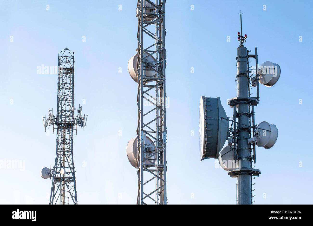 Broadcast relay station antennas at rising. Telecommunications towers with blue clear sky. Stock Photo