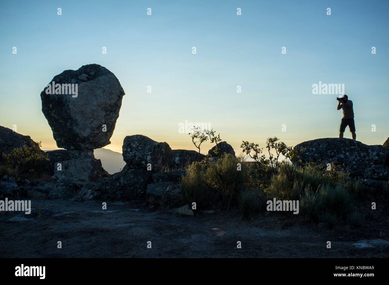 Silhouette of a photographer shooting sun rising above the mountain. Montanchez Famous megalithic monument, Caceres, Spain. Stock Photo