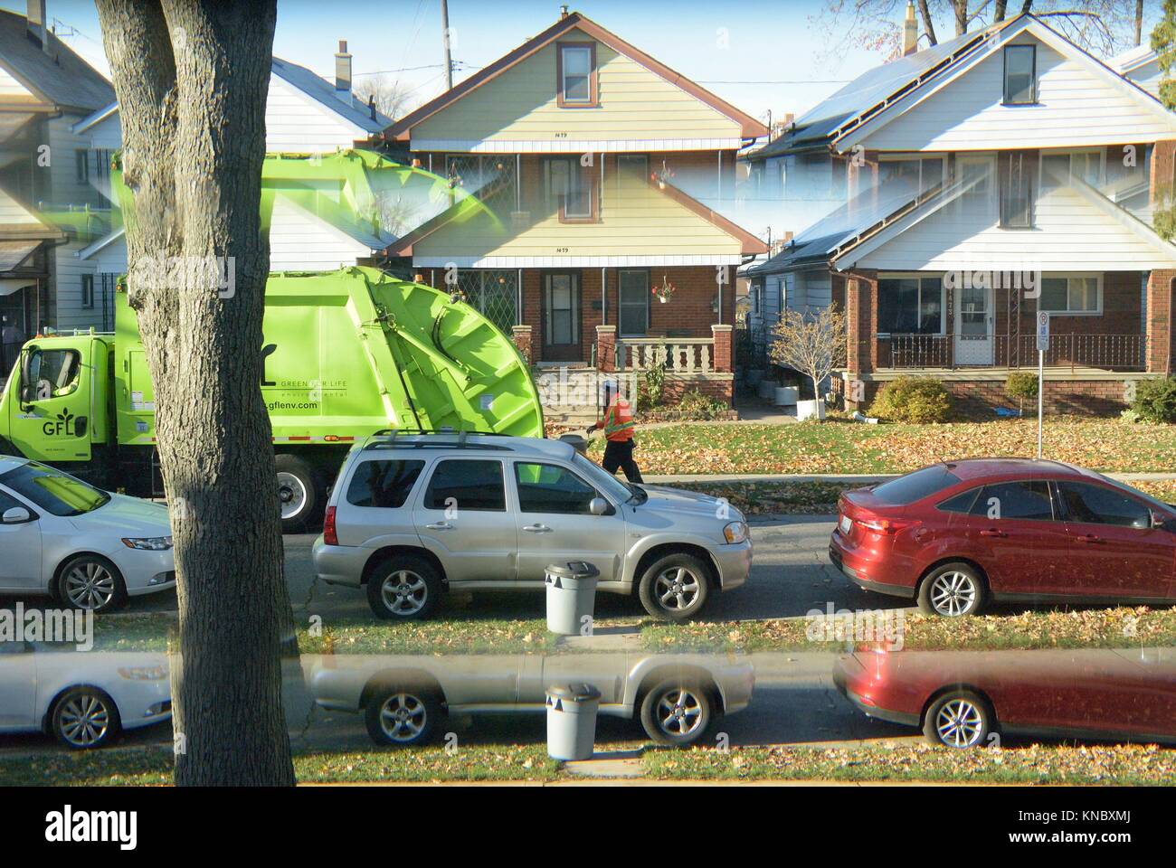 Garbage pick up day as seen through a front door window giving a split image, Windsor, Ontario. Stock Photo