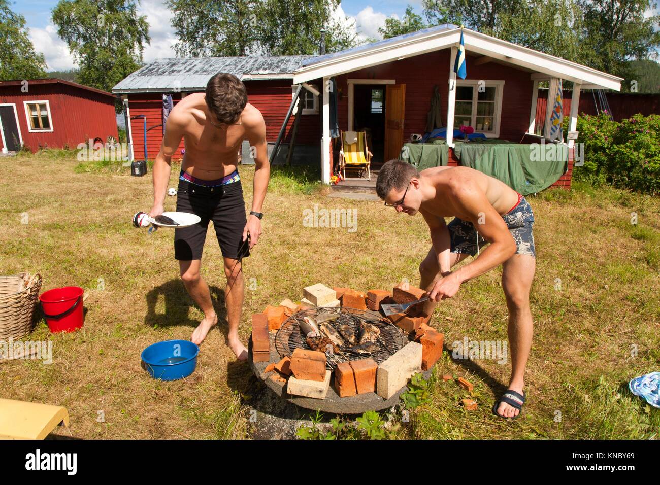 Brothers grilling fish, Northern Sweden. Stock Photo