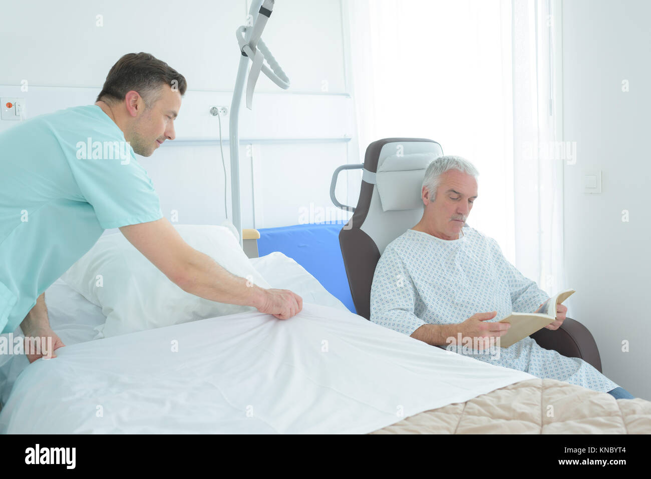 Auxiliary nurse making patient's bed Stock Photo